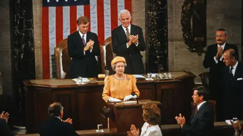 Dennis Brack/Pool via CNP/Getty Images Queen Elizabeth II in orange dress and hat is applauded by those present after addressing Congress in the House Chamber at the US Capitol in 1991. 