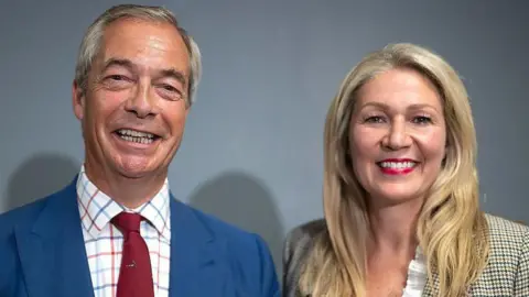 Getty Images Nigel Farage stood in to the left with Laura Anne Jones to the righjtj, in front of a grey background