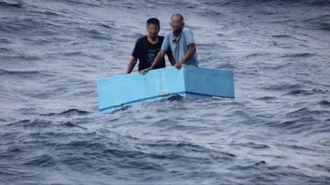 Two men inside a cooling box in the middle of the sea
