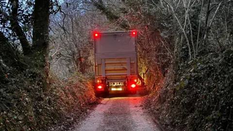 A lorry trapped in a very narrow country lane.