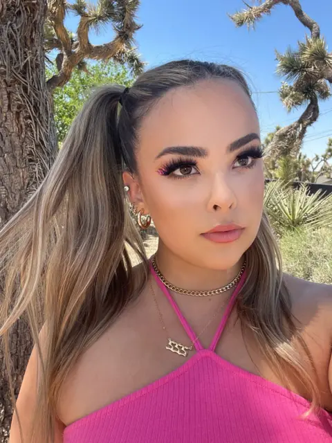 Ali Calder Picture of Ali Calder in a pink top and gold jewellery.