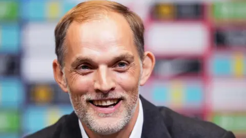 PA Media German manager Thomas Tuchel smiles in a grey blazer.