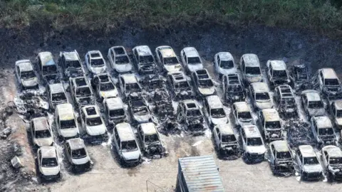 Eddie Mitchell A row of burnt out cars.