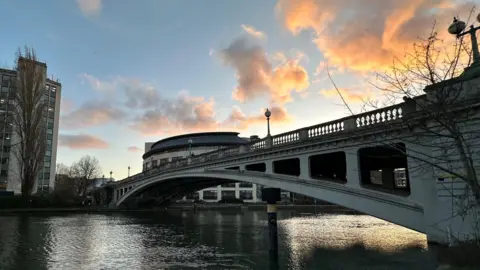 EmmaH A bridge over glistening water with blue and orange sky. 