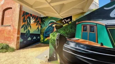 Guildford Borough Council A large mural showing a kingfisher and a narrowboat on walls beneath a bridge
