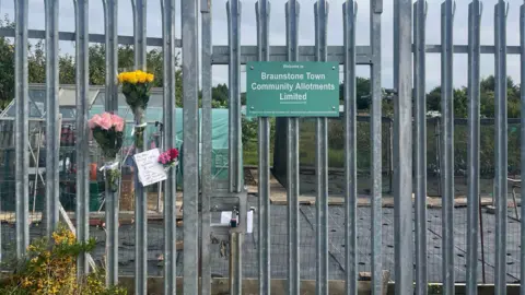 Floral tributes placed on fencing at allotment