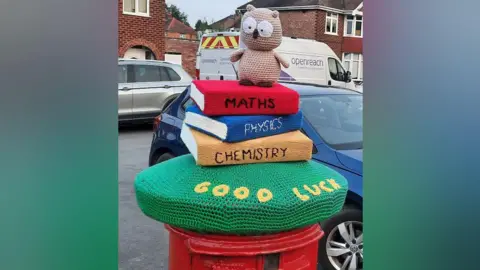 Sue Cockroft Postbox topper showing an owl sitting on a pile of schoolbooks