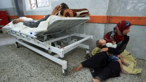 A Palestinian wounded by gunfire near an aid distribution centre in central Gaza, sits on the floor at al-Shifa hospital, in Gaza City (11 June 2025)