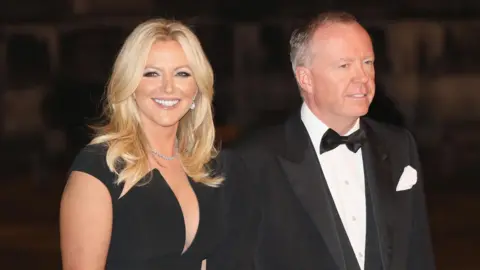 Getty Images Baroness Mone and her husband Doug Barrowman wearing evening dress at an event in 2017.