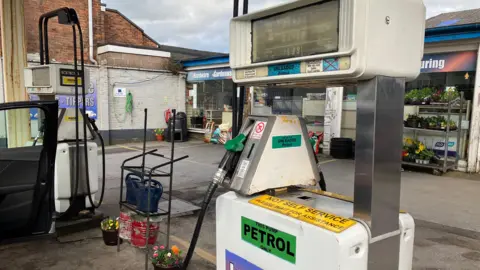 A petrol forecourt with two pumps on show and a shop in the background.