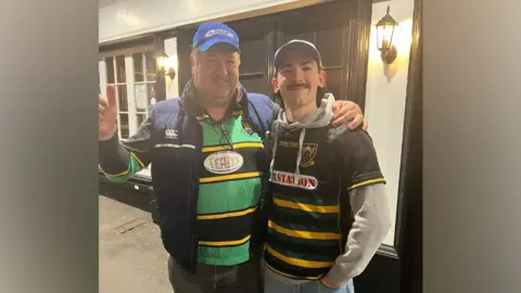 Supplied Chris Sansome and Matthew Sansome stand side by side with their arms over each other's shoulders. Both are wearing Northampton Saints jerseys.