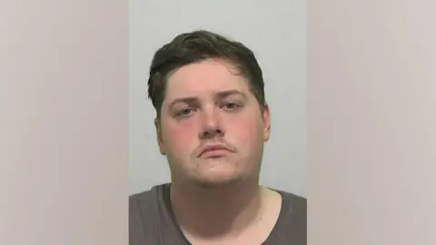 Northumbria Police A mugshot of Bradley Makin. He is wearing a brown T-shirt and has brown hair and a moustache.
