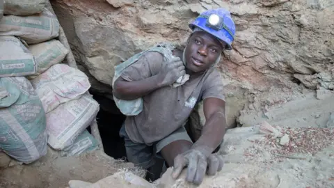 Aaron Ufumeli/EPA A miner carries a bag with ore as he comes out of a mine shaft in Shamva, Zimbabwe - Friday 9 June 2023