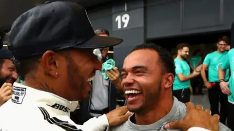 Getty Images Nic Hamilton looking at his brother Lewis smiling and laughing together.