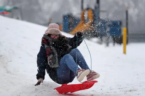 AFP A woman travels on a sled down a slope at Farnborough in Hampshire