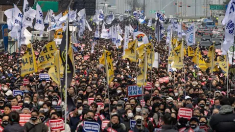 Getty Images A huge sea of people in a protest crowd, holding flags and banners and posters written in Korean