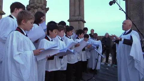 Choristors in white gowns sing from atop Magdalen Tower.