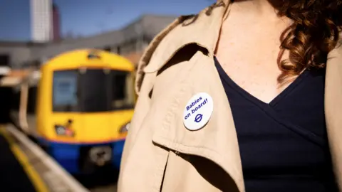 TfL A woman wearing a "Babies on Board" badge.