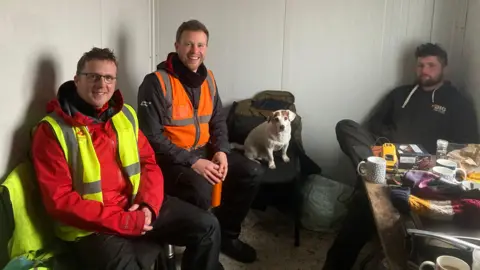 Peatland restoration workers having a break in a cabin with a dog.