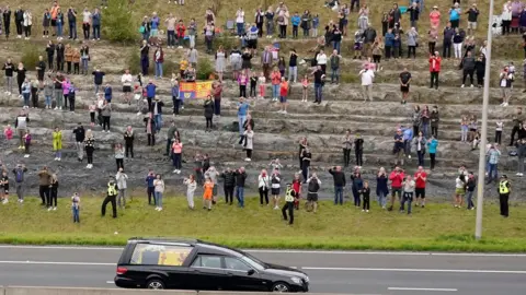 PA Media The hearse carrying the coffin of Queen Elizabeth II travels past crowds on its way into Edinburgh