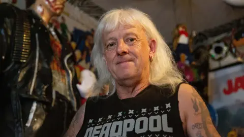 Man with white hair standing next to a 6ft Terminator 