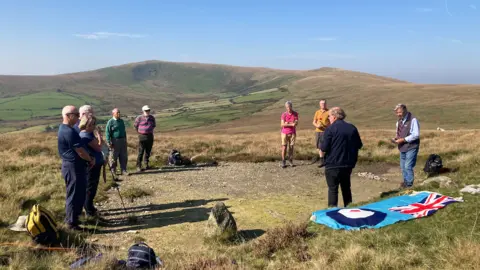 BBC News: People stood in a circle at the crash site