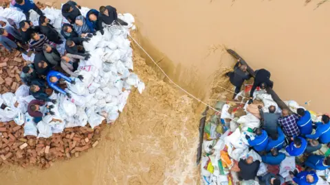 Getty Images Aerial view of people working to block a dyke breach at a section of Fenhe River in Jishan County.