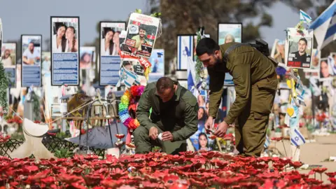 Os soldados israelenses da EPA acendem velas em um local memorial para as vítimas do ataque do Hamas no Festival de Música da Supernova em 7 de outubro de 2023, perto de Kibutz Reim, sul de Israel (31 de janeiro de 2025)