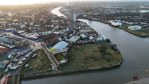 A drone image of the North Quay area in Great Yarmouth, depicting the mouth of a river flowing through a built-up area of the town