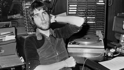 Getty Images A black and white picture of BBC Radio disc jockey Johnnie Walker in a radio studio, UK, 23rd November 1971. 