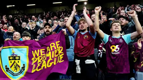Burnley fans in the crowd at Turf Moor celebrate after their side secured promotion