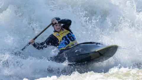 Nancy Geary Photography Eoghan Kelly competing, paddling in his canoe, surrounded by white water