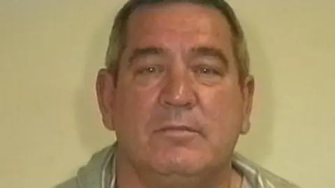 Stanley Carnall is pictured. He is in front of a blank background and is wearing a grey shirt and a grey hooded jacket 