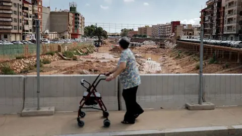 Getty Images A woman walks on a bridge overlooking a riverbed full of mud