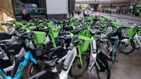 Lime and Human Forest e-bikes parked across the pavement on 8 October 2024 in London. 