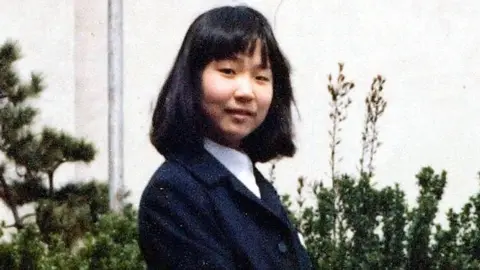 AFP Megumi Yokota aged 13, in school uniform outside her school, in April 1977. She was kidnapped later that year.