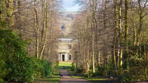 LDRS A path leads through the woodland - with Towneley Hall seen in the distance through the trees 