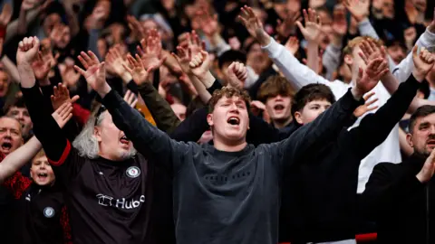 Bristol City Bristol City fans in the stands sing in support of their team in the match against Hull City at Ashton Gate. Many of them have their arms outstretched as they sing