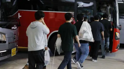 EPA Repatriated South Korean workers detained in a US Immigration and Customs Enforcement raid at a Georgia factory queue to board buses at Incheon International Airport in Incheon, South Korea, 12 September 2025.