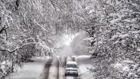 A 4x4 makes its way through a snow-covered road in Scotton, Harrogate, North Yorkshire