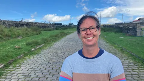 Photograph of Fran Healey from the Rooley Moor Neighbourhood Forum. The picture is taken with the Cotton Famine Road above Rochdale in the background.