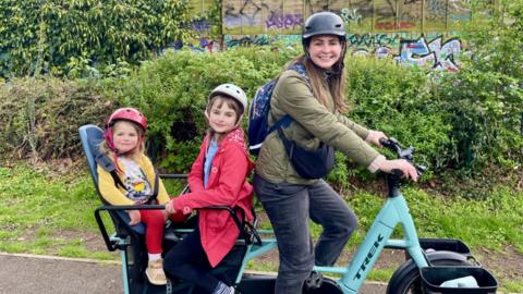 Myra on an electric bike with her two kids