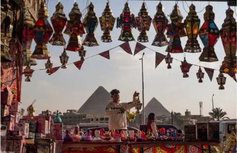Getty Images Man cleaning lanterns. There is a display of lanterns of different colours.