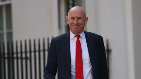 Newly appointed Chancellor of the Exchequer John Healey leaves 10 Downing Street on 20 July 2026, wearing a red tie and black jacket.
