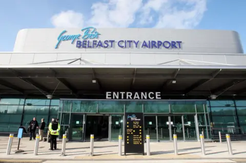 PA Media The exterior of Belfast City Airport which features a glass front with a sign above which reads: "George Best Belfast City Airport". 