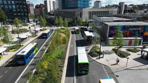 Swindon Borough Council An artist's impression of the planned works, with buses going along two roads in both directions between high rises in a city.