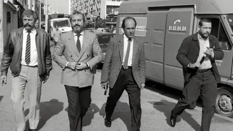 AFP Judge Giovanni Falcone (second from left), surrounded by armed bodyguards, arrives 21 October 1986 in Marseille, France