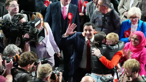 PA Media Scottish Labour leader Anas Sarwar with Maureen Burke after winning the Glasgow North East seat at Emirates Arena in Glasgow