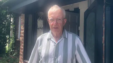 Alexander Stevanovic/BBC A man in glasses and striped shirt