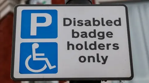 PA Media A parking sign stating "disabled badge holders only" in black text on a white background. To the left of the text are two parking symbols, a letter P and a wheelchair symbol, both in white on blue backgrounds.